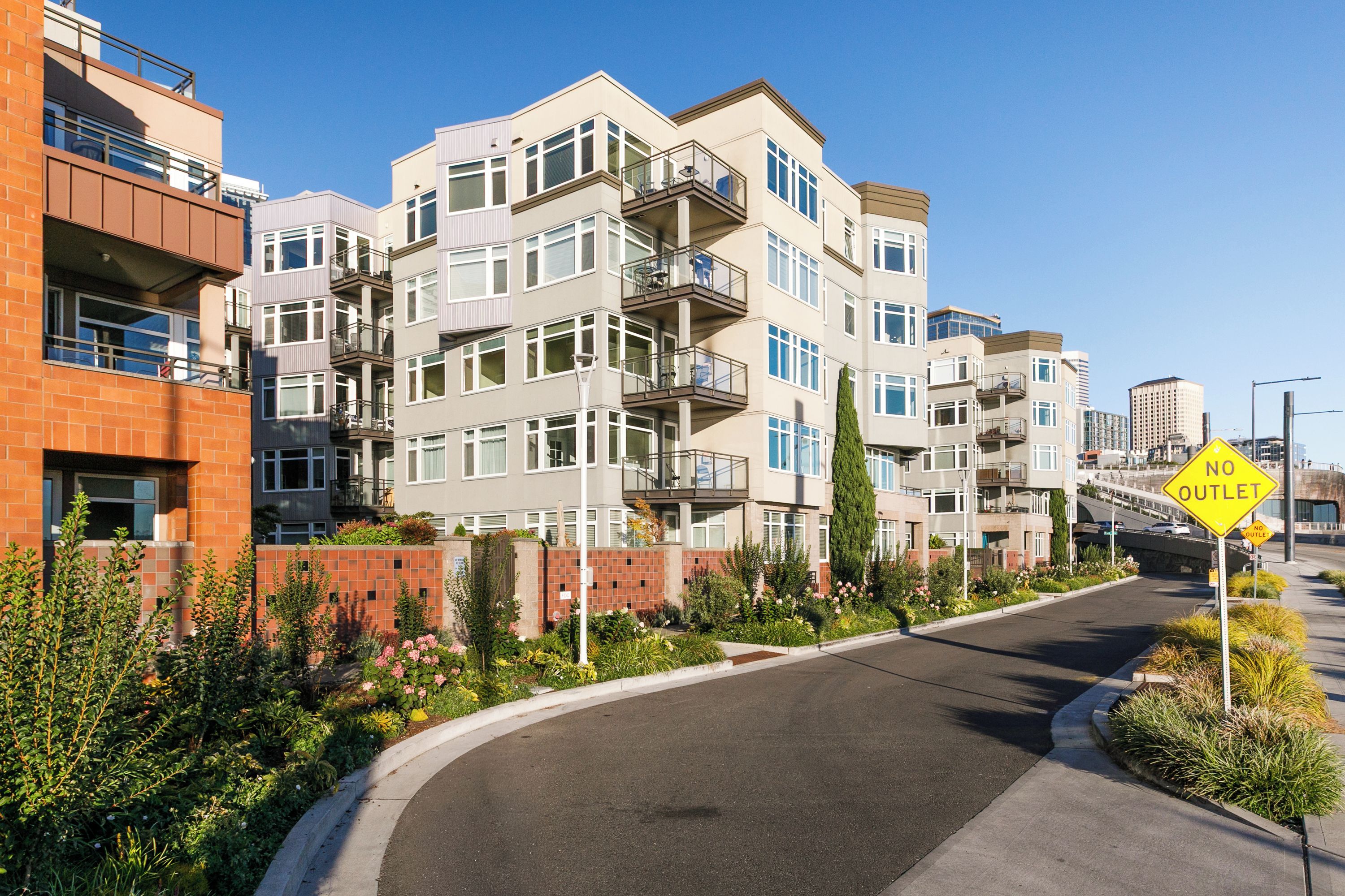 A multi-story residential building with balconies, a curved driveway, and a 'NO OUTLET' sign.