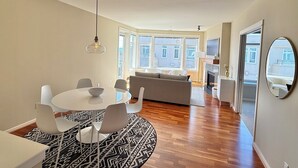 Ett modernt vardagsrum med matplats, soffa och öppen spis.