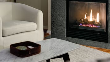 A modern living room with a white sofa, a marble coffee table, and a fireplace with visible flames.