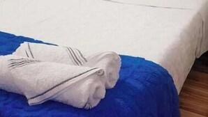 A bed with white bedding and a blue blanket, a folded white towel, and a wooden floor. - Apartment a few steps from the main square  (Villa de Leyva)