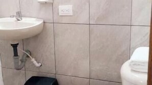 A bathroom with a toilet, sink, and black trash bin. - Apartment a few steps from the main square  (Villa de Leyva)