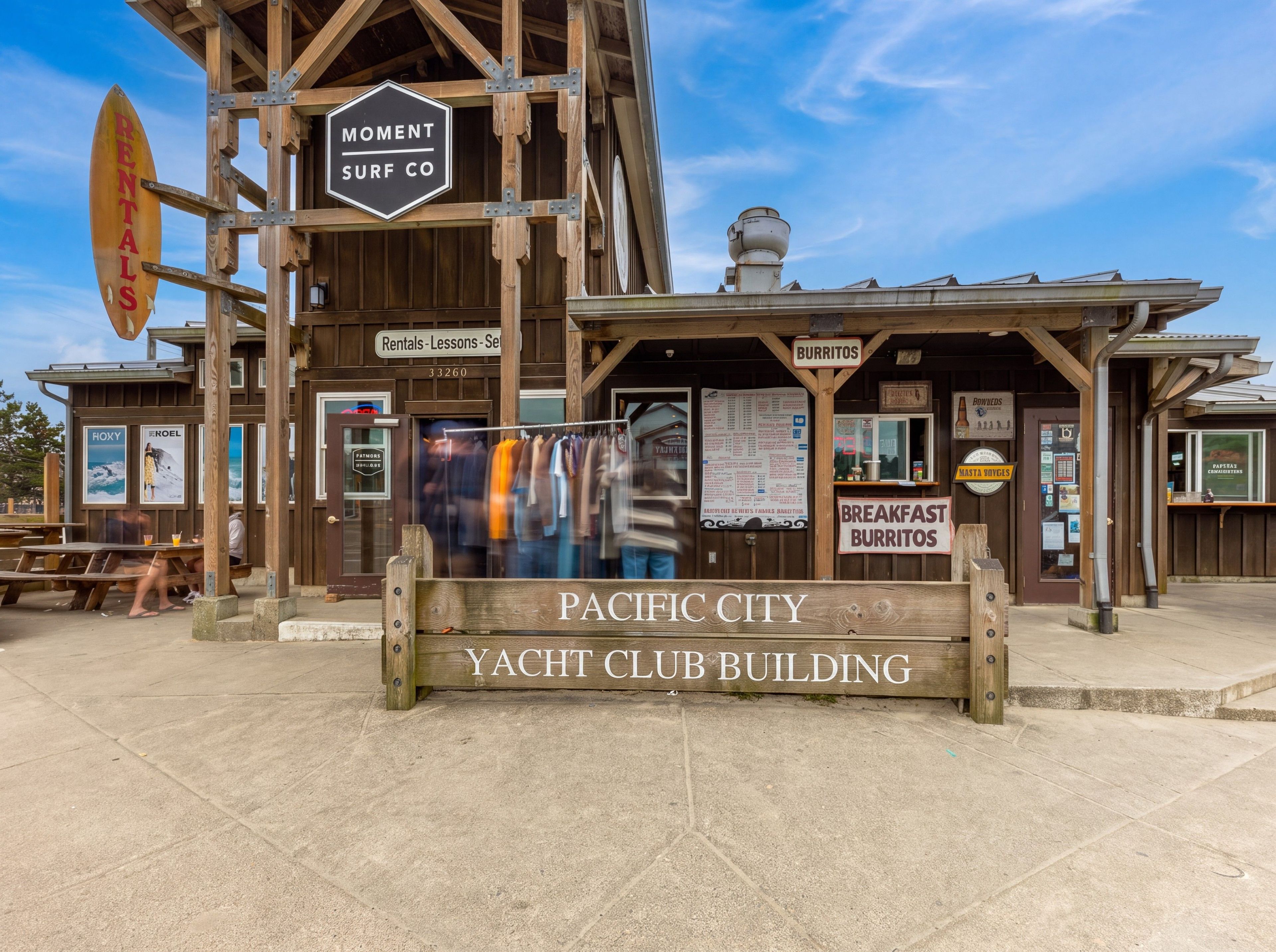 A wooden building with signs for 'Rentals - Lessons - Surfing' and 'Breakfast Burritos'.