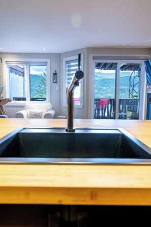 Eine Küche mit Spüle, ein Essbereich mit Stühlen und Blick ins Freie.