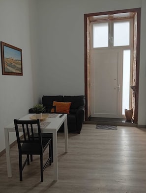 A dining area with a table, chairs, a black sofa with an orange pillow, a potted plant, and a framed picture on the wall. - Casa San Gregorio in the historic center of Telde, Las Palmas, Gran Canaria. (Telde)