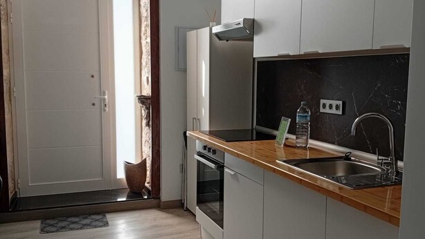 Een moderne keuken met een houten aanrecht, een RVS-spoelbak en een inbouwoven.