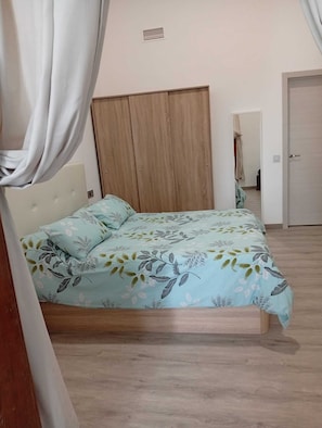 A bedroom with a bed, a wooden wardrobe, and a door. - Casa San Gregorio in the historic center of Telde, Las Palmas, Gran Canaria. (Telde)