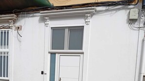 Een gebouw met een witte gevel, een dubbele deur met een raam en een zichtbare elektriciteitskast.