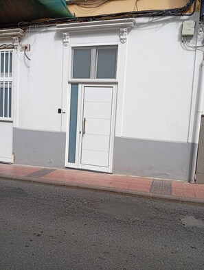 A building with a white facade, a double door with a window, and a visible electrical box. - Casa San Gregorio in the historic center of Telde, Las Palmas, Gran Canaria. (Telde)