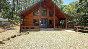 A wooden cabin with a porch, large windows, and a gravel driveway. - Private Cabin Retreat w/Hot Tub, Fire Pit & Loft (Broken Bow)