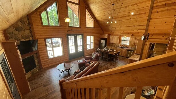 A cabin interior with a loft bedroom, a dining area, and a kitchen. - Private Cabin Retreat w/Hot Tub, Fire Pit & Loft (Broken Bow)