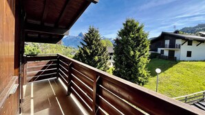 Een balkon met houten hekwerk met uitzicht op een bergachtig landschap.
