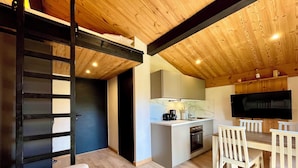 Een kleine keuken met een televisie, een eethoek met stoelen en een bank.