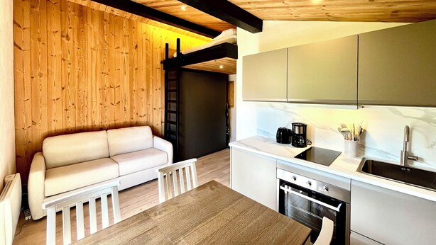 Een moderne keuken met een eethoek, houten wanden en een witte bank.