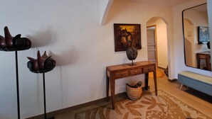 Een hal met een houten console tafel, een grote spiegel en een schilderij aan de muur.