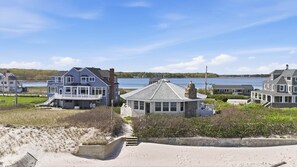 A coastal property with multiple houses, a sandy beach, and a body of water in the background.