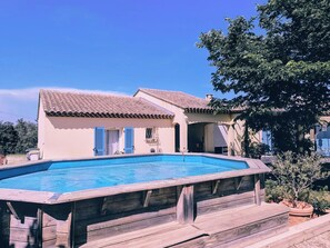 Ein Haus mit Swimmingpool, Ziegeldach und Holzterrasse.