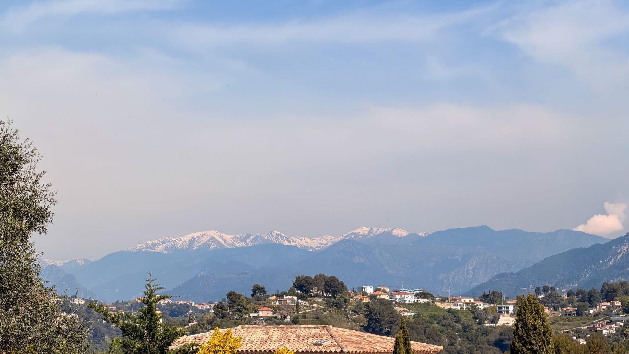 A mountainous landscape with a village in the foreground, featuring terraced houses and a clear sky.