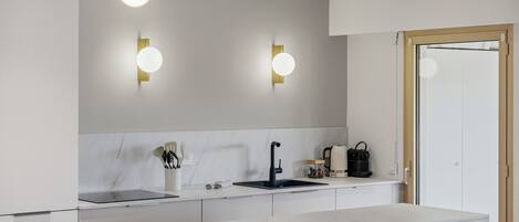 A modern kitchen with a white countertop, black faucet, and two wall-mounted lights.
