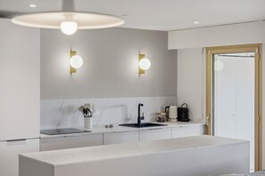 Une cuisine moderne avec un plan de travail blanc, un robinet noir et deux lampes fixées au mur.