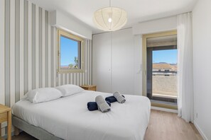 Une chambre à coucher avec un lit, une table de chevet, une fenêtre et une porte.