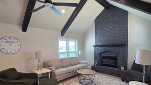 Una sala de estar con chimenea, ventilador de techo y un reloj en la pared.