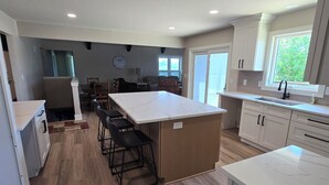 Una cocina moderna con una isla central, suelo de madera y armarios blancos.