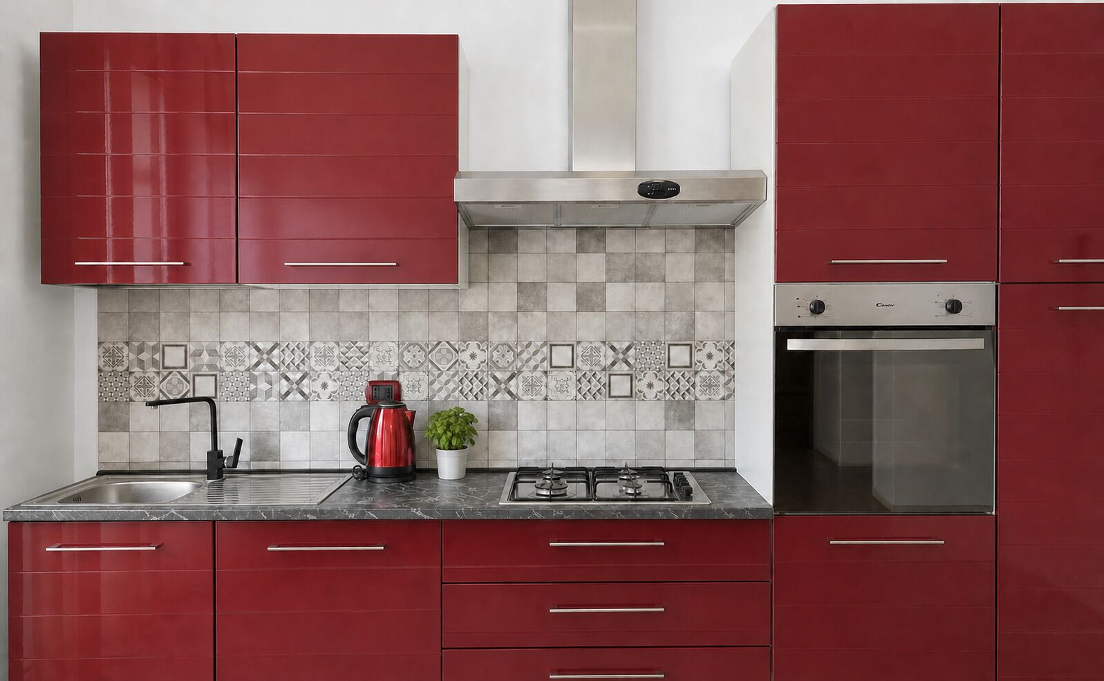 A kitchen with red cabinets, a stainless steel range hood, a built-in oven, and a patterned backsplash.