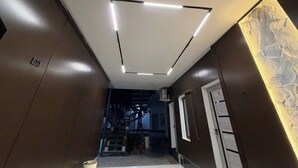 A hallway with a modern ceiling design, a door on the right, and a textured wall on the left. - Usmoon Hotel (Tashkent)
