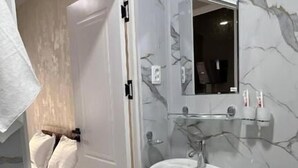A bathroom with a marble wall, a pedestal sink, a toilet, and a door leading to a bedroom. - Usmoon Hotel (Tashkent)