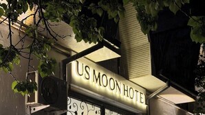 A building with a sign reading 'US MOON HOTEL' and a large window with decorative patterns. - Usmoon Hotel (Tashkent)