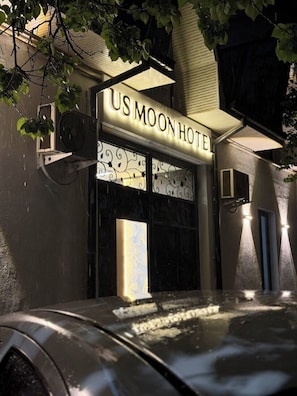 A building with a sign reading 'US MOON HOTEL' and a large window with decorative patterns. - Usmoon Hotel (Tashkent)