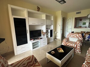 A living room with a TV, white cabinets, a sofa, and a coffee table. - Beautiful apartment 85m2, with terrace in a +++ site, 5 swimming pools; 1 k from the sea (Manilva)