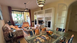 Ein Wohnzimmer mit einem Glastisch, gestreiften Sofas und einer weißen Unterhaltungsecke.