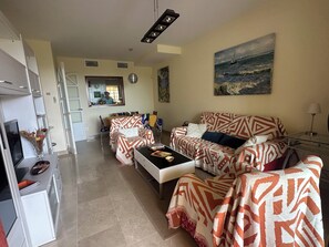 A living room with a sofa set, a coffee table, a TV, and a painting on the wall. - Beautiful apartment 85m2, with terrace in a +++ site, 5 swimming pools; 1 k from the sea (Manilva)