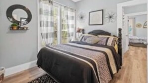 Un dormitorio con cama, espejo y ventana con cortinas.