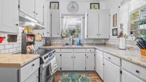 Una cocina con armarios blancos, una estufa y un lavabo.