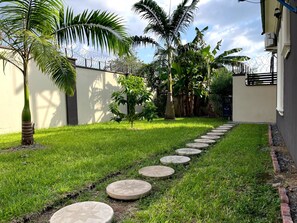 Ein Garten mit einem Weg, Palmen und einem Gebäude.