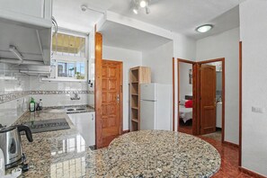 Eine Küche mit Granit Arbeitsplatten, einem Edelstahlkocher und einer Holztür, die in ein Schlafzimmer führt.