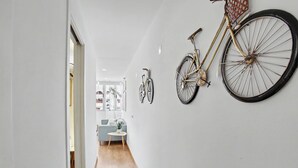 En hall med en cykel som hänger på väggen, ett litet runt bord med en växt och en soffa i bakgrunden.