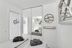 Un dormitorio con una cama, una bicicleta, un espejo y un estante en la pared.
