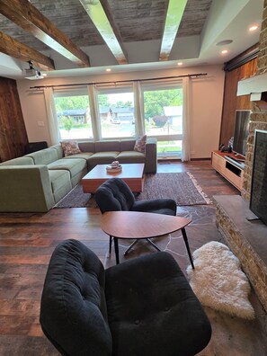 A modern living room with a sectional sofa, a coffee table, a black armchair, a fireplace, and large windows. - Spacious 4 bdr house in Medinah within walking distance of Medinah Country Club (Medinah)