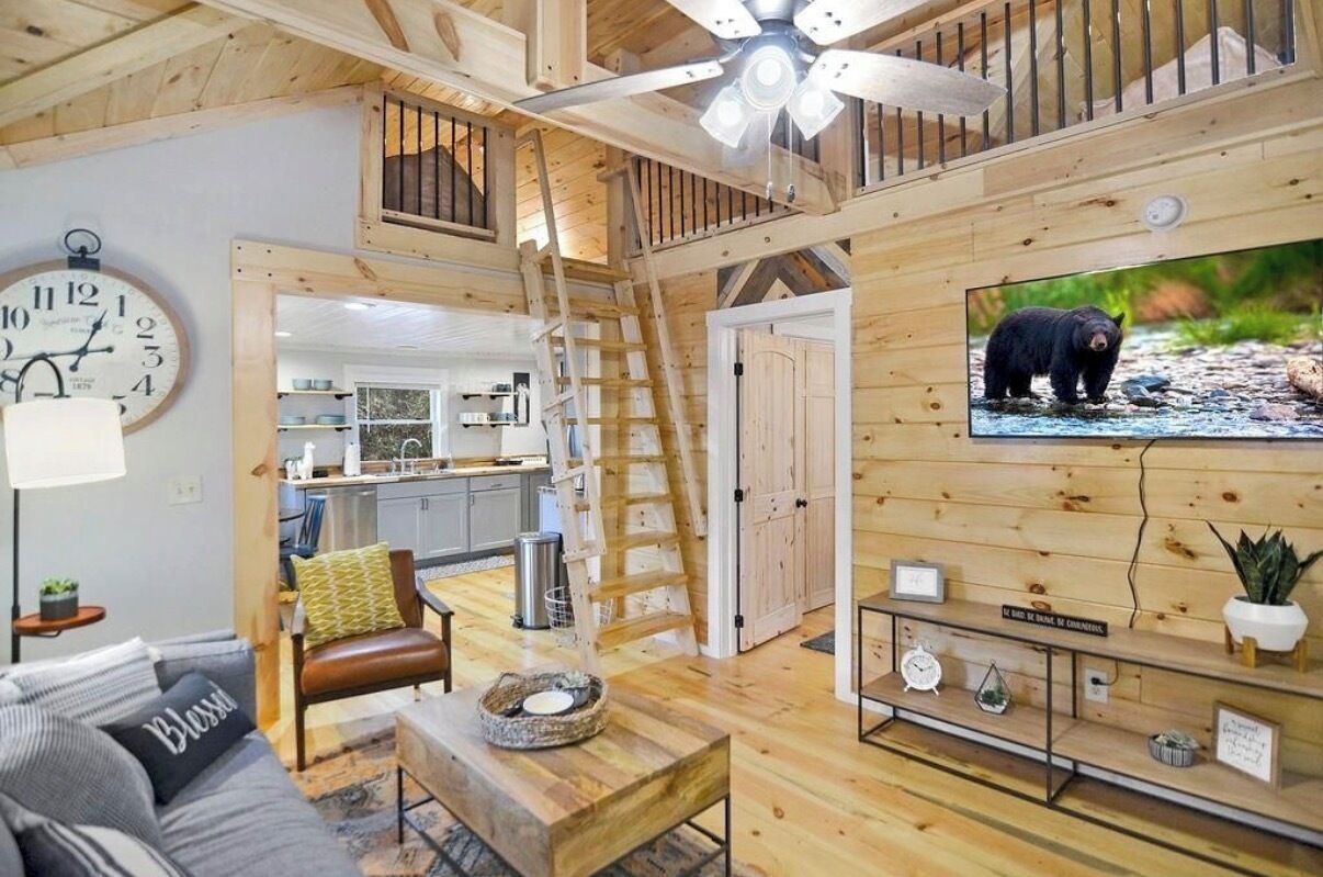 A wooden interior with a kitchen, dining area, and a TV displaying a bear.