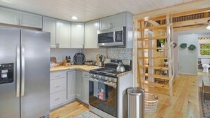 Eine Küche mit Kühlschrank, Herd, Mikrowelle und Holzregalen.