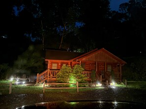 Een houten blokhut met een veranda, een kleine tuin en een vijver.