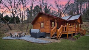 Eine Holzhütte mit Veranda, Sitzgelegenheit im Freien und einem Feuerkorb.