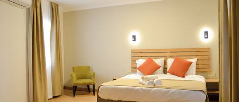 A hotel room with a bed, a chair, and a headboard with lights.