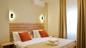 A hotel room with a wooden headboard, two pillows, a bed with white bedding, a nightstand, and an air conditioning unit. - Kale Otel Bodrum (Bodrum)