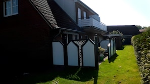 Ein Wohnhaus mit Backsteinfassade, einem Balkon, einem weißen Zaun und einem gepflegten Rasen.