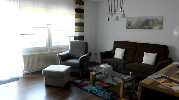 Una sala de estar moderna con sofá, sillón, reposapiés y una mesita de centro.
