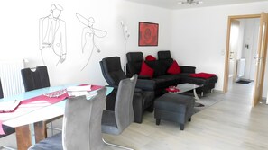 Ein modernes Wohnzimmer mit einer Couch, Sesseln, einem Couchtisch und einem Esstisch mit Stühlen.
